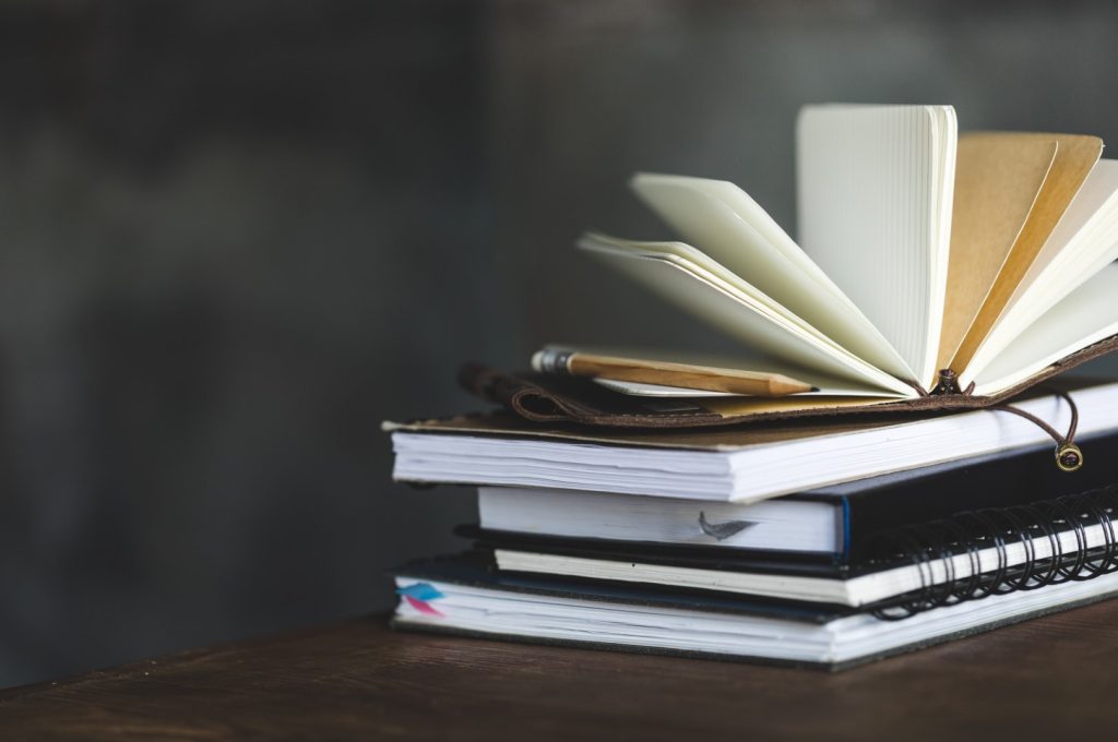 stack of books and diaries on dark grey with copy space